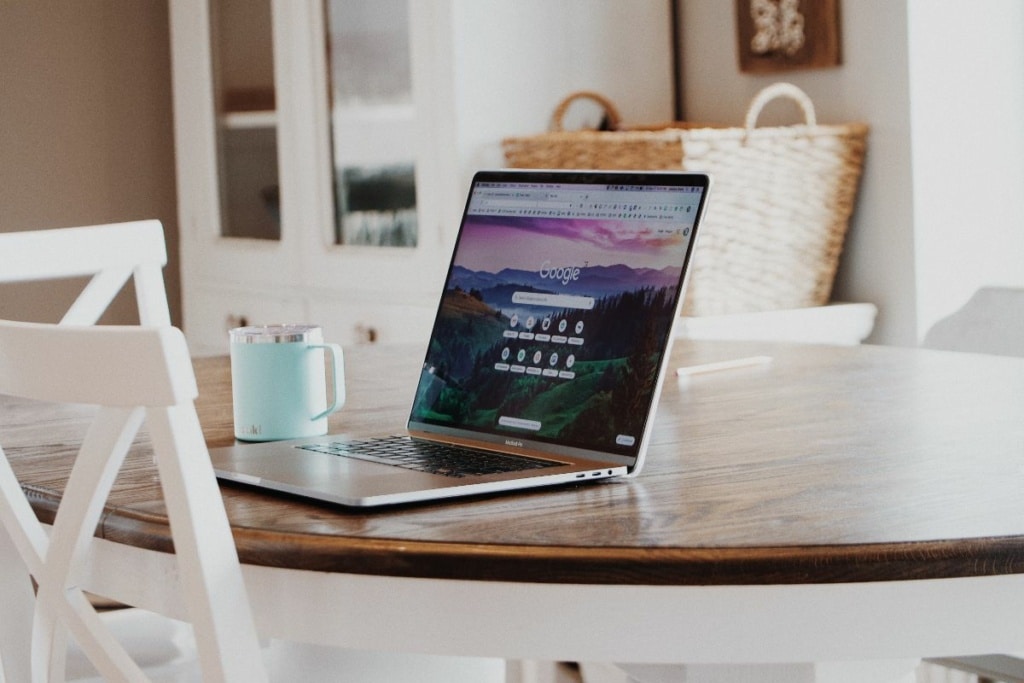 Mac posé sur une table, ouvert sur la page d'accueil Google.