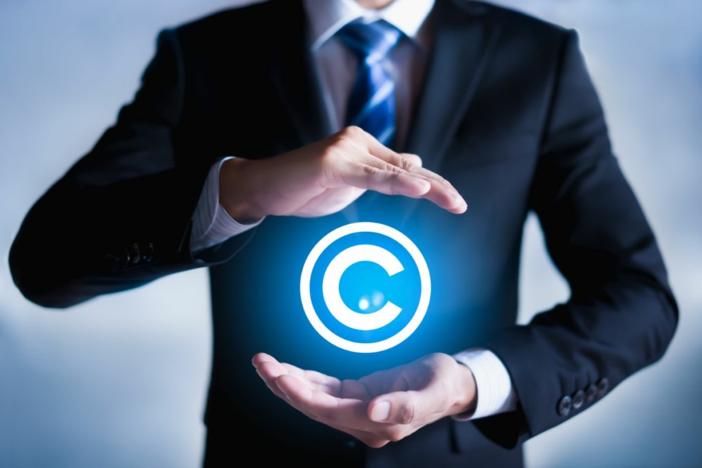 Un homme en costume tient le sigle Copyright entre ses mains.