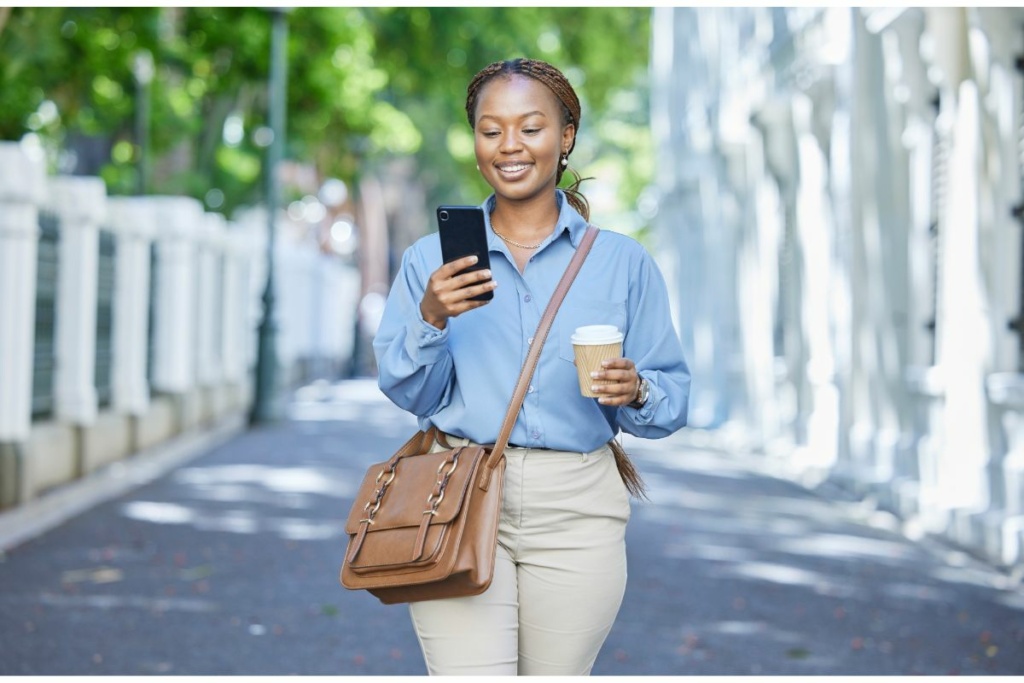 Une femme regarde son téléphone en marchant dans la rue.