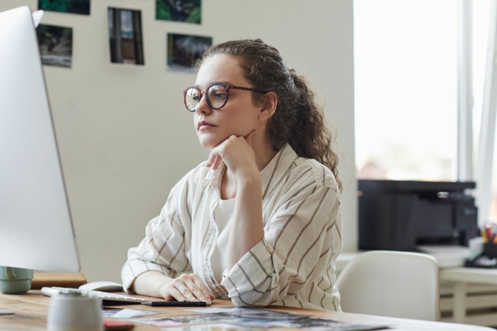 Une femme réfléchit devant son ordinateur