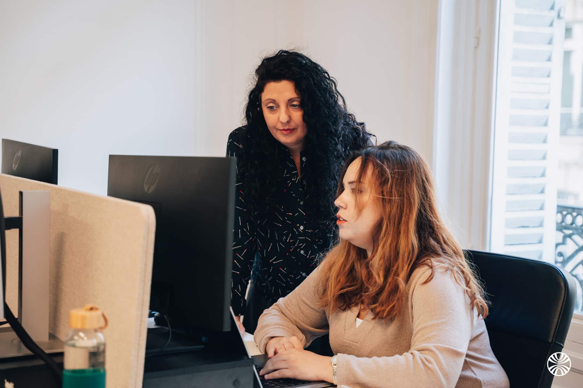 Deux femmes travaillant devant un ordinateur au bureau.
